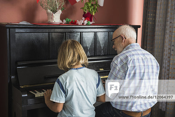 Großvater und Enkel spielen Klavier