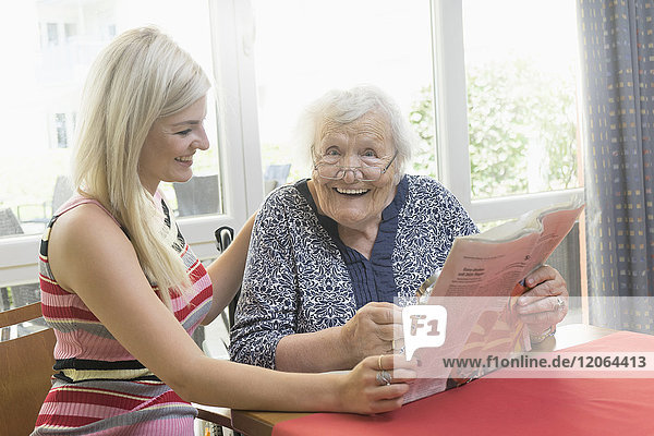 Senior woman reading newspaper with her daughter
