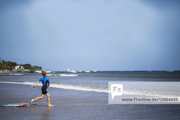 Junge läuft mit Surfbrett ins Meer