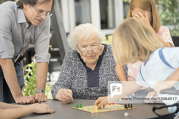 Ältere Frau mit Familie bei einem Brettspiel im Altersheim