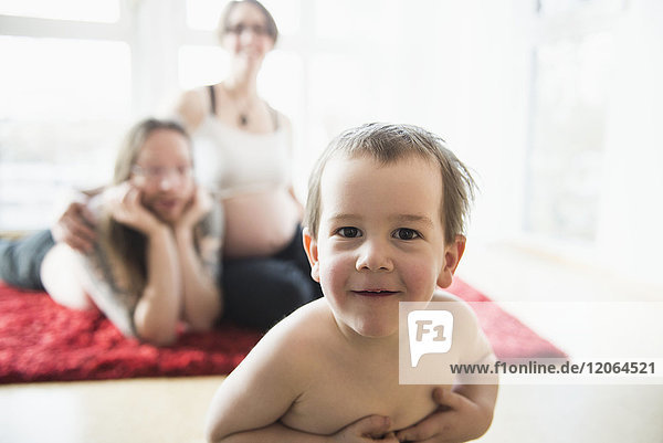Porträt eines kleinen Jungen mit schwangeren Eltern im Hintergrund