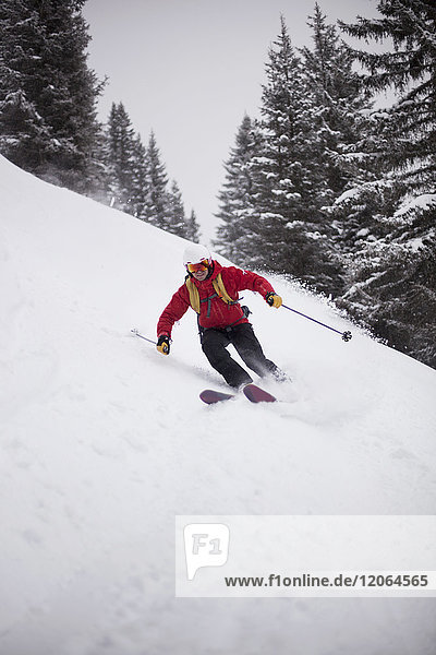 Mann beim Skifahren bergab auf Schnee