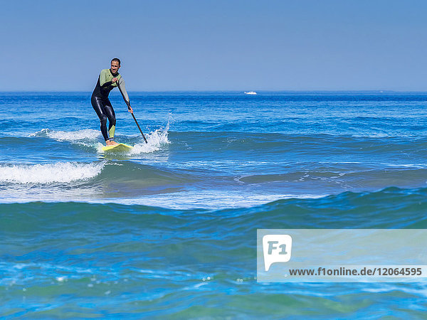 Mann beim Surfen mit einem Stand Up Paddling Board am Strand von Sopelana