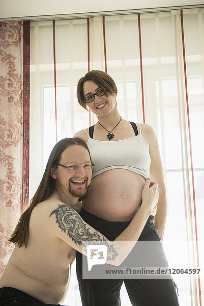 Porträt eines Mannes  der den Bauch seiner schwangeren Frau umarmt