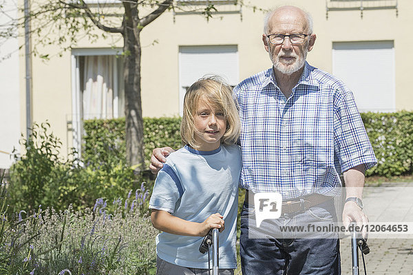 Junge hilft Großvater mit Gehhilfe im Altenheimpark