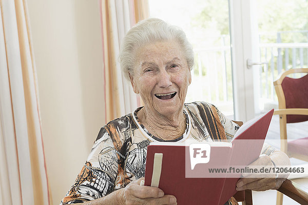 Porträt einer glücklichen älteren Frau  die im Altersheim ein Buch liest