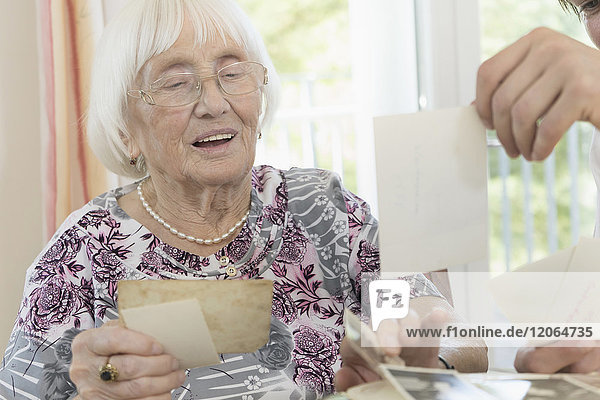 Ältere Frau betrachtet Fotos mit Hausmeister im Altersheim