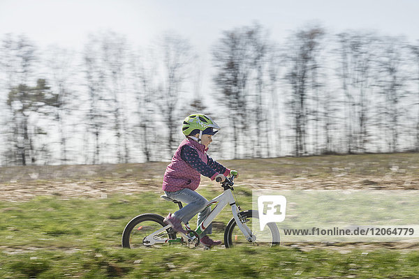 Kleines Mädchen fährt Fahrrad auf einem Feld