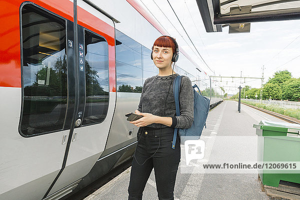 Frau mit Kopfhörer auf dem Bahnsteig
