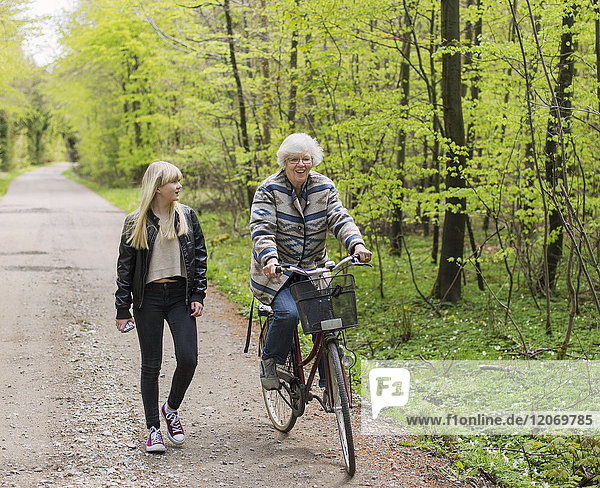Großmutter und Enkelin mit Fahrrad auf Waldweg
