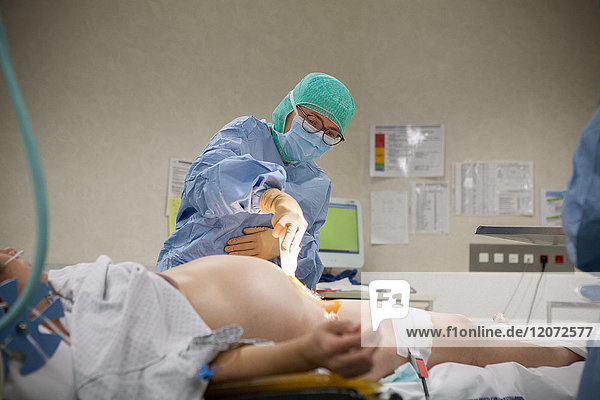 Reportage aus der Entbindungsstation des Krankenhauses Métropole Savoie in Chambéry  Frankreich. Eine geplante Kaiserschnittentbindung. Ein Assistenzarzt desinfiziert die Einschnittstelle.