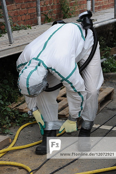 Preparing a worker on an asbestos removal site in the north of France. Regulatory clothing for each worker consists of overalls  a mask  boots and gloves. Professional tape is added everywhere that asbestos could come into contact with clothes to ensure impermeability.
