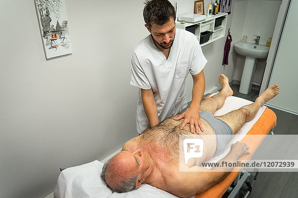 Reportage in an osteopathy practice in Héyrieux  France. Osteopathy session for a 73-year old man suffering from thoracic block causing strain between the vertebrae and ribs.