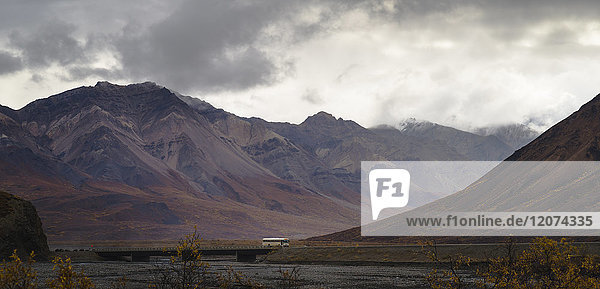 Tourist bus driving among mountains in the Denali National Park  Alaska  United States of America  North America
