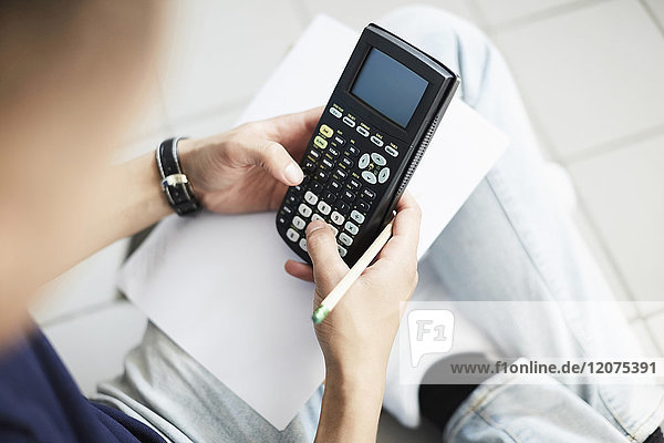 Cropped image of man using calculator while studying at laundromat