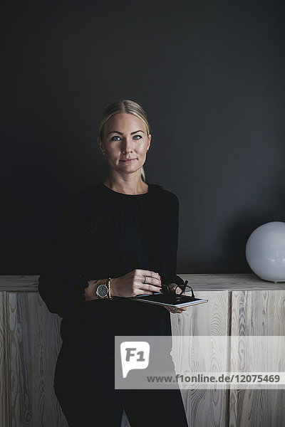 Porträt einer selbstbewussten Geschäftsfrau  die ein digitales Tablett in der Hand hält.