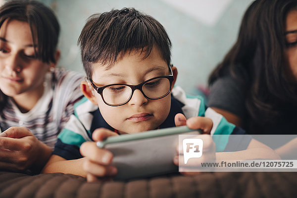 Nahaufnahme eines behinderten Jungen mit Hilfe eines digitalen Tabletts im Bett zu Hause