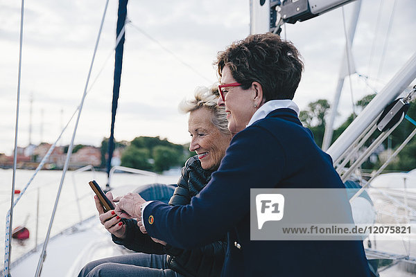 Smiling senior women using mobile phone on yacht