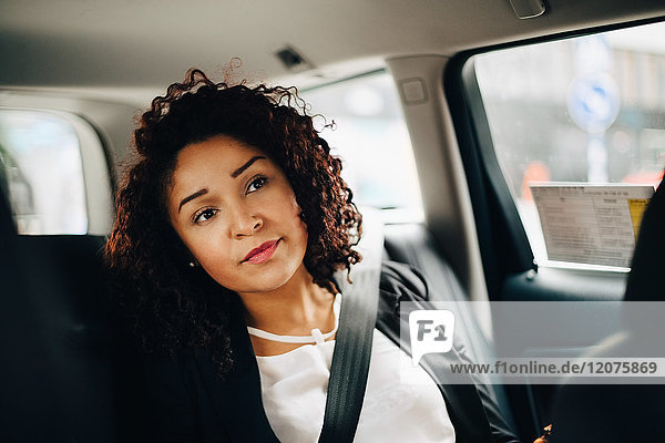 Mittlere erwachsene Geschäftsfrau im Taxi sitzend