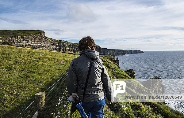 Ireland County Clare Woman walking along Cliffs of Moher