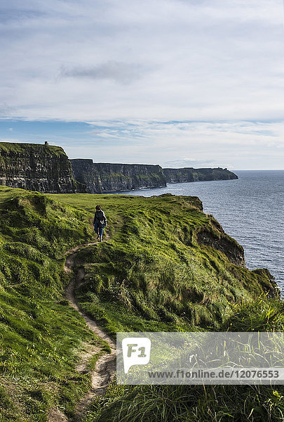 Irland  Grafschaft Clare  Frau geht entlang der Cliffs of Moher