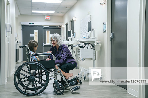 Smiling doctor comforting girl in wheelchair