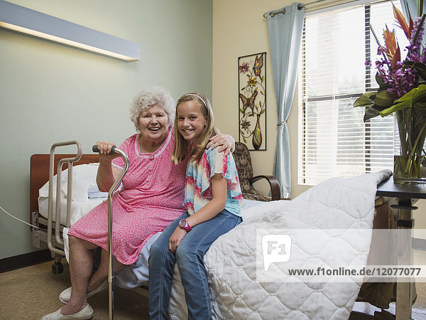 Smiling Caucasian woman sitting on bed with granddaughter