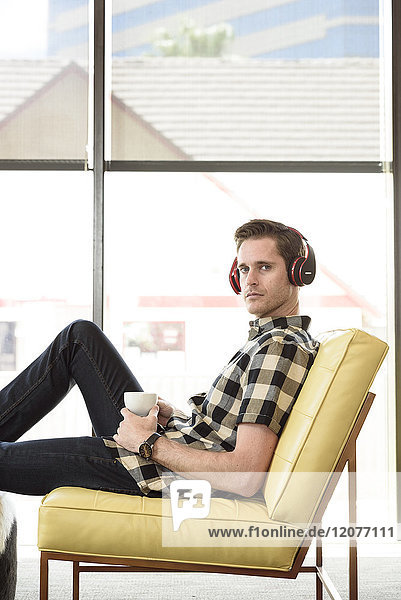 Caucasian man drinking coffee and listening to headphones