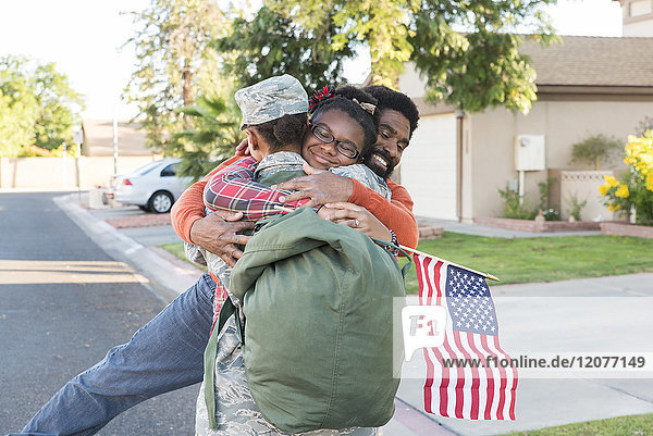 Schwarze Soldatin  die Mann und Tochter umarmt