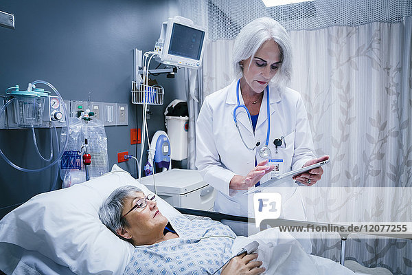 Arzt mit digitalem Tablet im Gespräch mit einem Patienten
