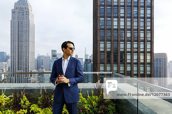 Caucasian businessman holding apple on urban rooftop