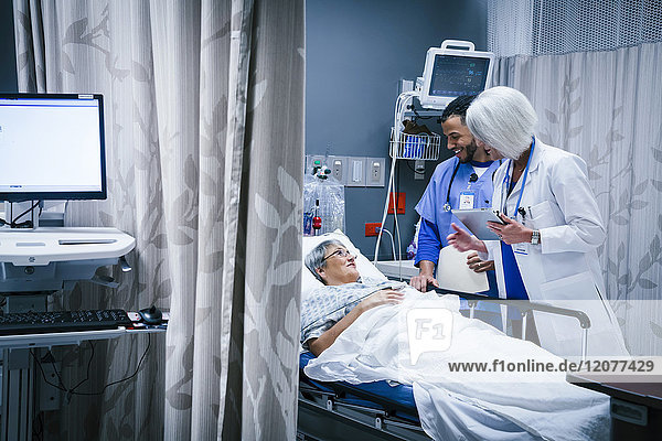Doctor and nurse talking with patient in hospital bed