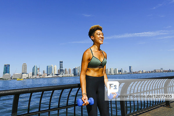 Mixed race woman lifting dumbbells at waterfront