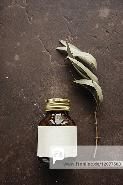 Alternative medicine jar with blank label near leaf