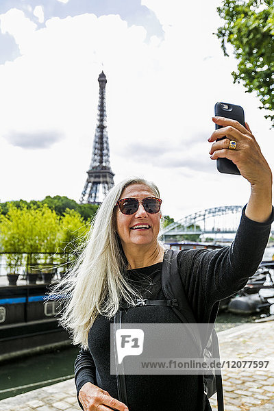 Kaukasische Frau posiert für Handy-Selfie in der Nähe des Eiffelturms