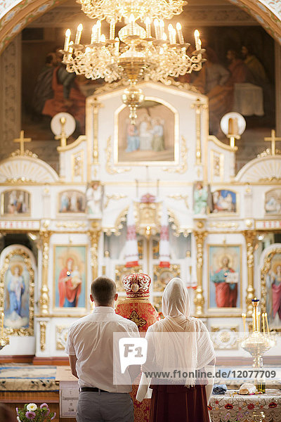 Ehepaar und Priester in der Kirche stehend