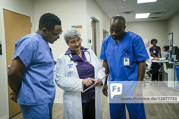 Arzt und Krankenschwestern diskutieren über das digitale Tablet