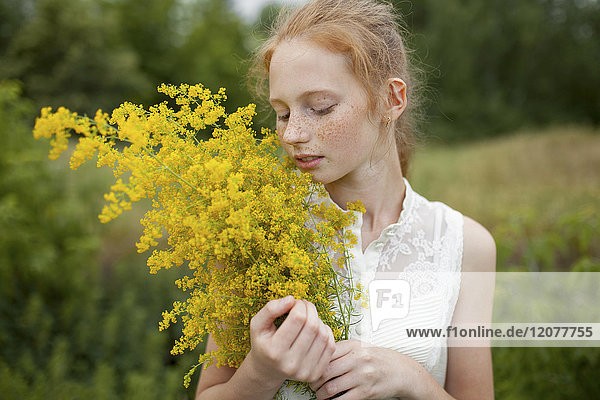 Caucasian girl smelling wildflowers