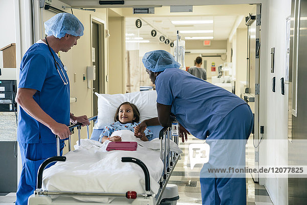 Krankenschwestern im Gespräch mit einem Mädchen auf einer Krankenhausbahre