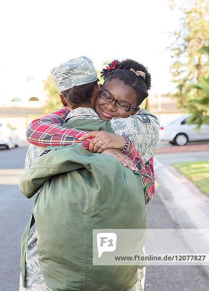 Schwarze Soldatin  die ihre Tochter auf der Straße umarmt