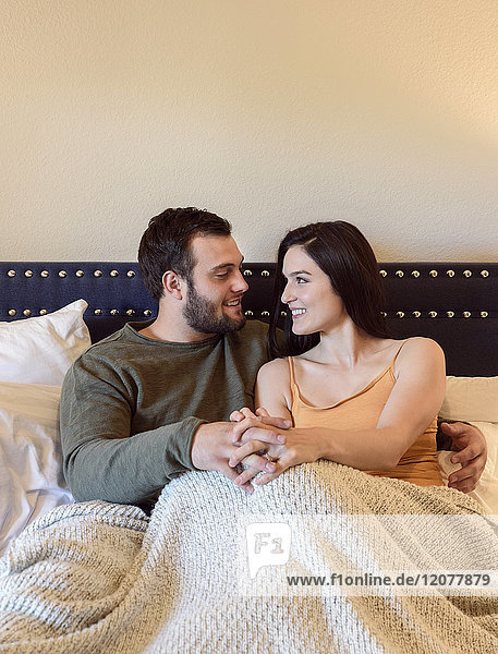 Kaukasisches Paar hält Hände im Bett