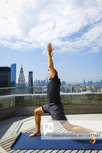 Caucasian man practicing yoga on urban rooftop