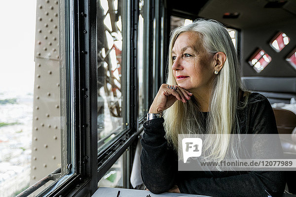 Kaukasische Frau bewundert die Aussicht aus dem Fenster eines Restaurants