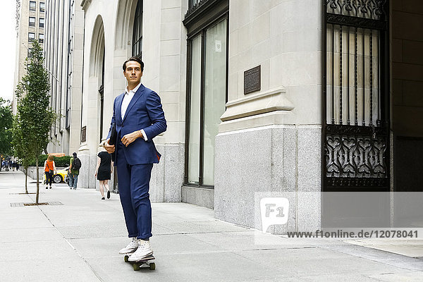 Caucasian businessman skateboarding on urban sidewalk