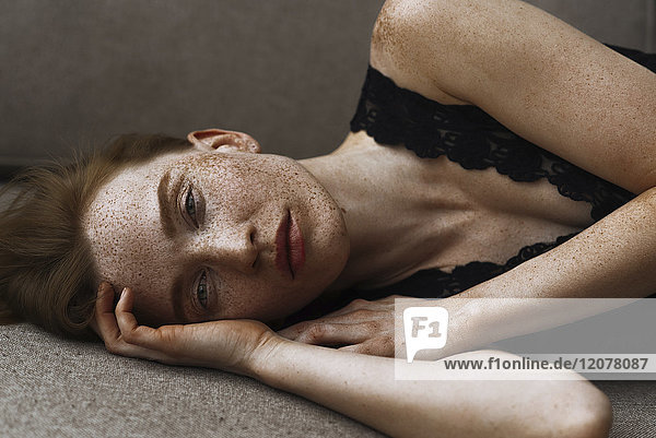 Pensive Caucasian woman with freckles laying on floor