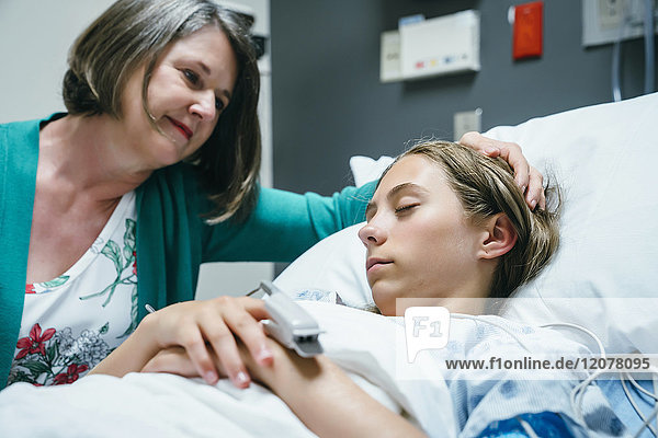 Caucasian mother comforting daughter in hospital