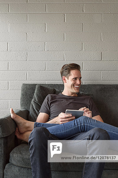 Legs of Caucasian woman on lap of man using digital tablet