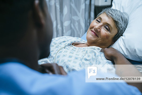 Krankenschwester spricht mit Patient im Krankenhausbett
