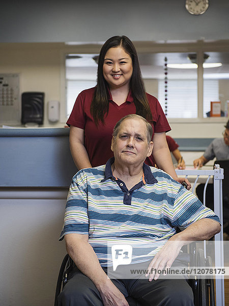Porträt einer lächelnden Krankenschwester und eines Patienten im Rollstuhl
