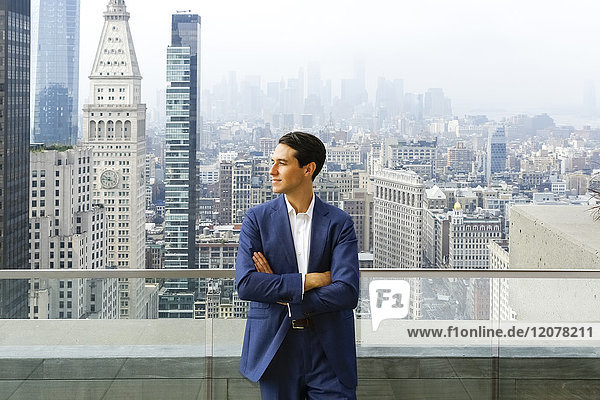 Caucasian businessman leaning on urban rooftop